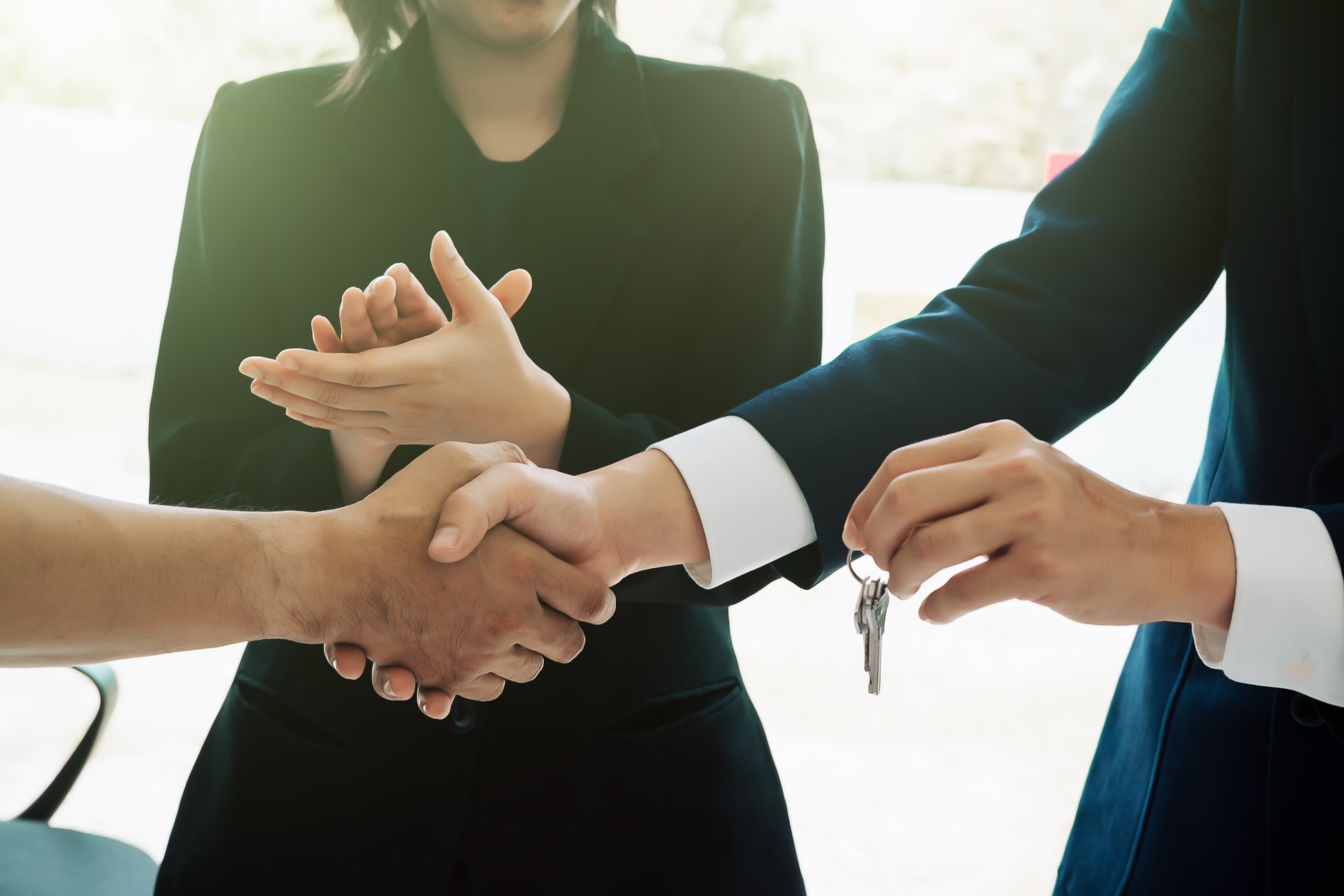 Estate Broker Giving Key and Shaking Hand of a Client